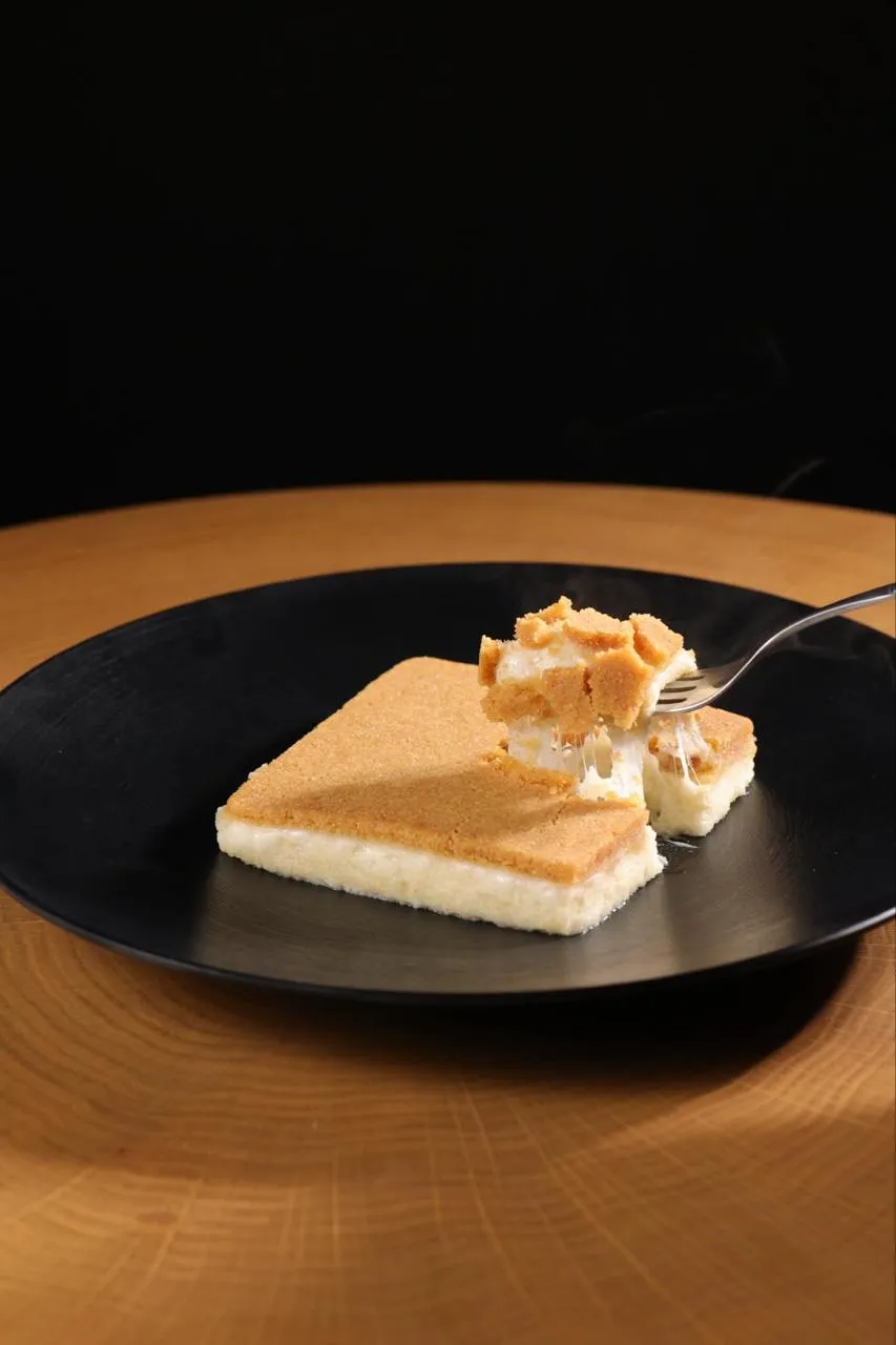 Knefeh tiède sur assiette, fourchette soulevant un morceau